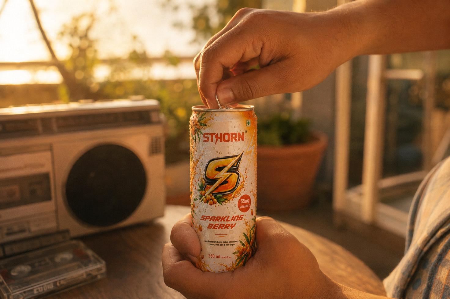 Hand opening a Sthorn Sparkling Berry can at golden hour, with a vintage boombox and cassette tapes in the background, evoking a nostalgic scene.